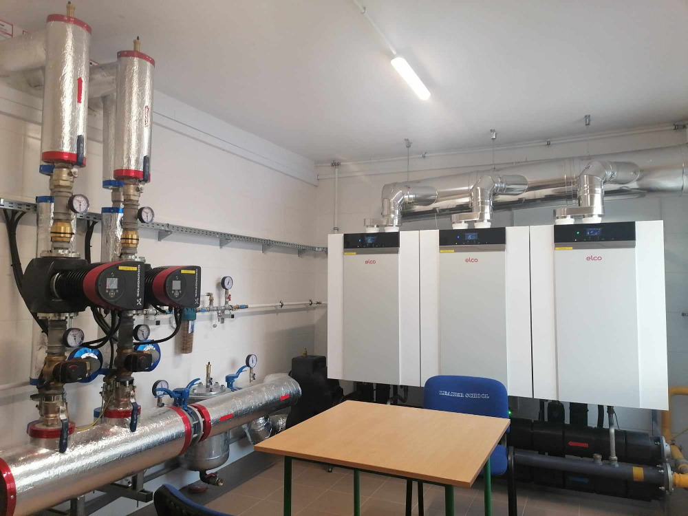 Pomieszczenie kotłowni gazowej, piece, stolik i instalacja gazowa. 