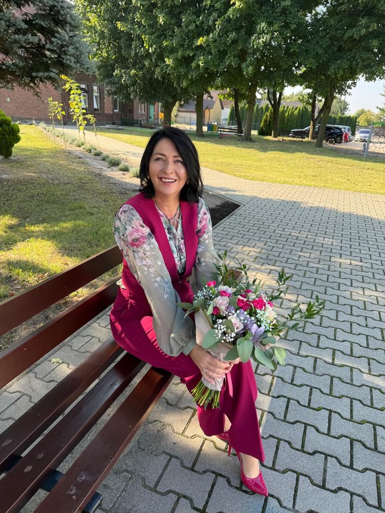 Kobieta siedzi na ławce z bukietem kwiatów. 